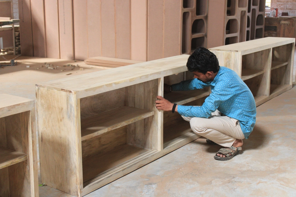 Quality control inspection of a wooden furniture piece in a factory.